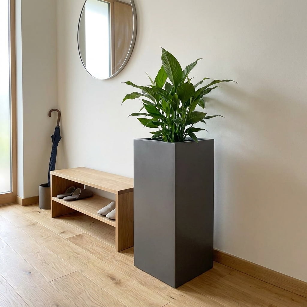 Anthrazit Metallic Pflanzkübel in Säulenform mit Einblatt neben einer Sitzbank im modernen Eingangsbereich