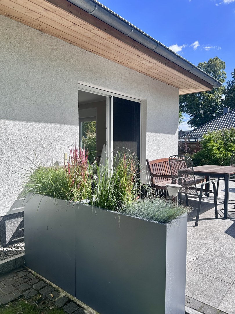 Pflanzkübel Fiberglas rechteckig 84x30x80cm anthrazit-metallic mit Ziergräsern als Raumteiler auf einer Terrasse