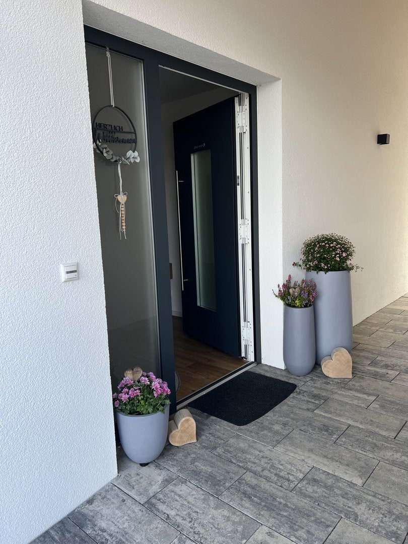 Pflanzkübel Fiberglas rund konisch D26xH56cm und D40xH80cm grau mit Chrysanthemen und Heide am Hauseingang