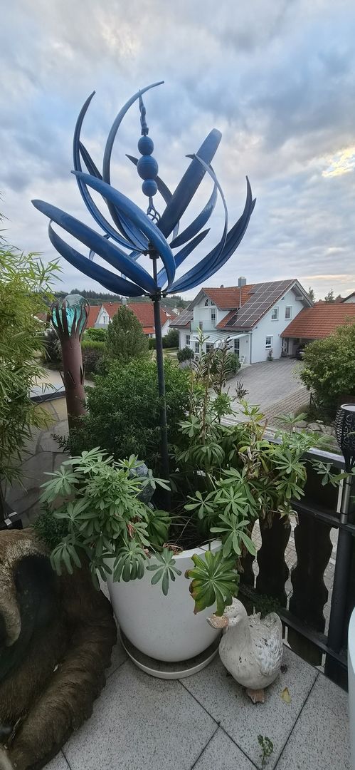 Pflanzkübel Fiberglas rund konisch D60xH60cm perlmutt weiß mit Staudenbepflanzung und blauem Windspiel auf einem Balkon